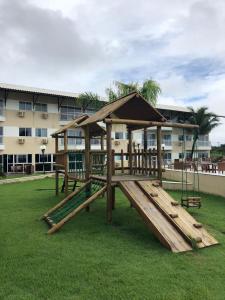 a wooden playground with a swing and a building at Muro Alto Suites - Marupiara in Porto De Galinhas