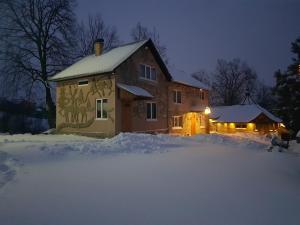 uma casa está coberta de neve à noite em Fazenda Kosiv em Kosiv