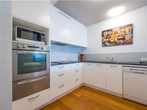 a kitchen with white cabinets and stainless steel appliances at Seaspray U4 21 Warne Tce in Caloundra