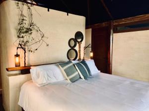 um quarto com uma cama branca com dois anéis pretos em Libelula Tulum Beachfront Hotel em Tulum