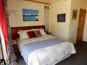 a bedroom with a large bed with a blue bedspread at Owls' Rest in Linkwater