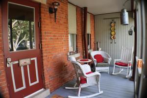 un porche con sillas de mimbre y una puerta roja en 50 Lincoln Short North Bed & Breakfast en Columbus