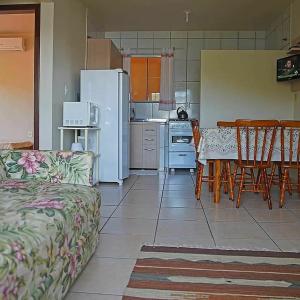 a kitchen with a couch and a table and a refrigerator at Pousada Porto dos Mares in Pinheira