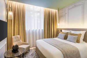 ein Schlafzimmer mit einem großen Bett und einem Stuhl in der Unterkunft Hôtel & Spa Les Sept Fontaines Best Western Premier in Tournus
