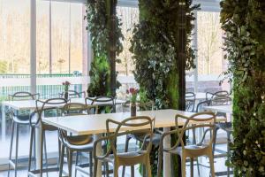 una fila de mesas y sillas en una habitación con plantas en Sure Hotel by Best Western Saint-Amand-Les-Eaux en Saint-Amand-les-Eaux