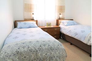 a bedroom with two beds and a desk and a window at Capon Cottage in Broken Hill