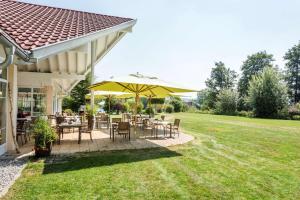 eine Terrasse mit Tischen und Stühlen und einem gelben Sonnenschirm in der Unterkunft Best Western Plus Parkhotel Maximilian Ottobeuren in Ottobeuren