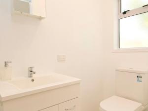 a white bathroom with a sink and a toilet at Bellbird Cottage - Lake Taupo Bach in Waitahanui