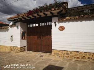 een wit gebouw met een houten deur met een bord erop bij Casa Azul Leyva in Villa de Leyva