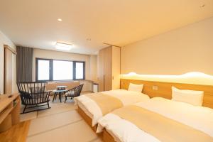 a hotel room with two beds and a table at Kyukamura Myoko in Myoko +39 photos