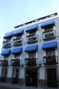 a white building with blue awnings and balconies at Hotel Diana in Puebla