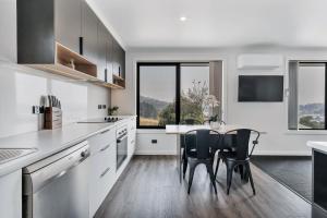 a kitchen with white cabinets and a table with chairs at Youngtown Executive Apartments - 2BR included, Free Parking & Wifi, Sofa Bed & Cot fee applies in Launceston