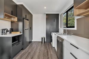 a kitchen with white cabinets and white appliances at Youngtown Executive Apartments - Host RNR Apartments in Launceston