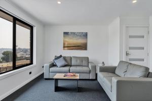 a living room filled with furniture and a window at Youngtown Executive Apartments - Host RNR Apartments in Launceston