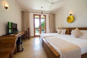 1 dormitorio con 1 cama y escritorio con TV en Kalu's Hideaway Udawalawe, en Udawalawe