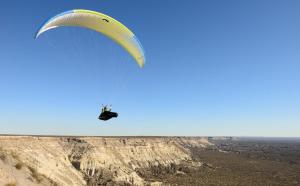 a person riding a parachute over a cliff at Calidez y comodidad. in General Roca