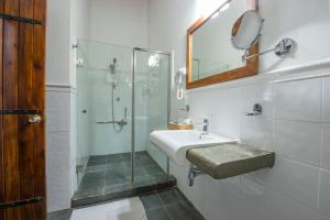 a bathroom with a shower and a sink and a mirror at Kalu's Hideaway Udawalawe in Udawalawe