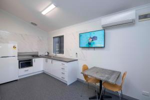 eine Küche mit weißen Geräten und einem Tisch mit Stühlen in der Unterkunft Karrinyup Waters Resort in Perth