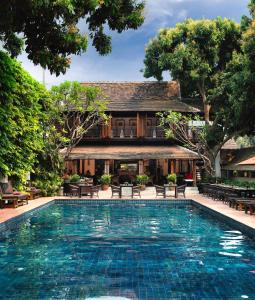 a swimming pool in front of a house at Tamarind Village in Chiang Mai