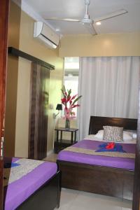 a bedroom with two beds with purple sheets and a window at City Lodge in Port Vila