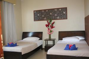 two beds in a hotel room with blue pillows at City Lodge in Port Vila