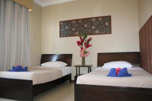 a bedroom with two beds and a vase of flowers at City Lodge in Port Vila