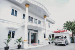 um edifício branco com um carro estacionado em frente em RedDoorz Syariah near Transmart Lampung em Bandar Lampung