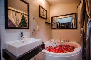 a bathroom with a sink and a tub filled with red roses at The Sanctuary Villa Battambang in Battambang