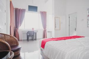 a bedroom with a bed and a table and a window at RedDoorz Syariah near Arafah Hospital Jambi in Jambi