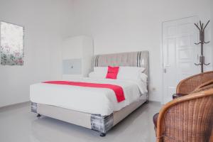 um quarto branco com uma cama grande e uma almofada vermelha em RedDoorz Syariah near Arafah Hospital Jambi em Jambi