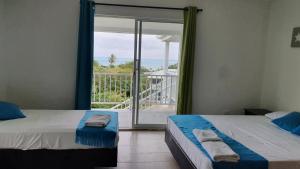 two beds in a room with a view of the ocean at Red Snapper Guest House in Providencia
