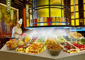 a chef standing behind a counter with fruits and vegetables at Sunway Pyramid Hotel in Kuala Lumpur