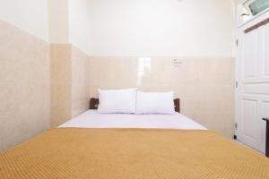 1 cama con sábanas blancas y almohadas en una habitación en Hotel Omah Ampel Syariah en Sukodono