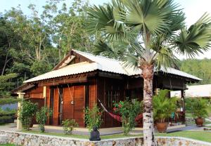 Villa Kelapa Langkawi في كواه: منزل خشبي أمامه نخلة