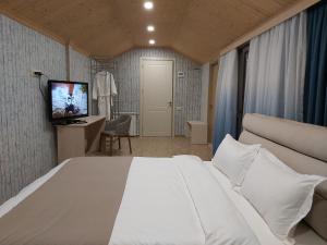 a bedroom with a large white bed and a television at VeraNda in Tbilisi City