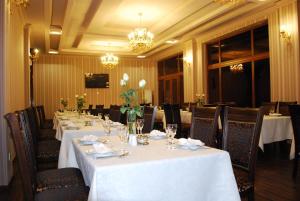 a dining room with white tables and chairs and a chandelier at Jahon Palace in Samarkand