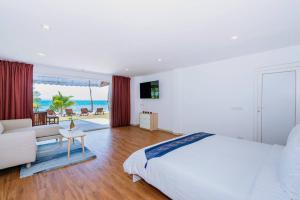 a bedroom with a bed and a living room with the ocean at Coral Cove Beachfront Villa - Koh Chang in Ko Chang
