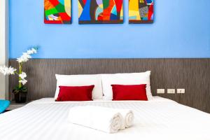 a bed with two red pillows and a blue wall at FX Hotel Pattaya in Pattaya South