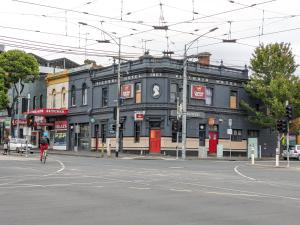 um edifício na esquina de uma rua com uma pessoa a andar de bicicleta em Queen Victoria Hostel em Melbourne