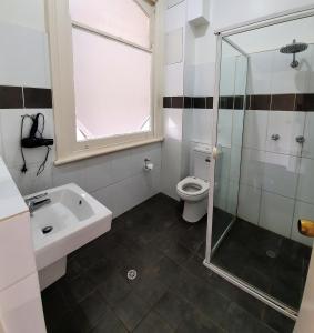 a bathroom with a toilet and a sink and a shower at Grand Hotel in Newcastle