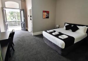 a bedroom with a bed and a desk and a window at Grand Hotel in Newcastle