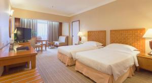 a hotel room with two beds and a flat screen tv at Bayview Hotel Melaka in Malacca
