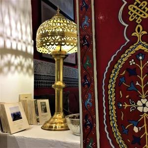 una lampada dorata su un tavolo con libri di Dar Sultan a Tangeri