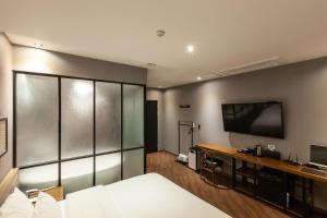 a hotel room with a bed and a flat screen tv at Beomil Brown Dot Hotel in Busan