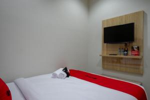 a room with a bed with a red and white blanket at RedDoorz @ Jalan Kartini Semarang in Semarang