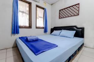 a bedroom with a bed with blue sheets and windows at Homestay Damandiri Prambanan Syariah in Salakan
