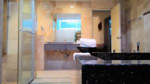 a bathroom with a sink and a shower and a mirror at Palm Island B&B in Gukeng