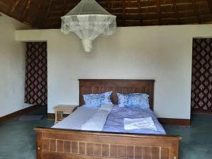 a bedroom with a large bed with blue pillows at Tangi Safari Lodge in Pakwach East