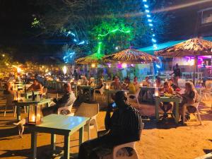a group of people sitting at tables at a restaurant at night at Surf Bar Mirissa in Mirissa