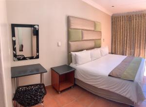 a bedroom with a large bed and a mirror at Polokwane Lodge in Polokwane